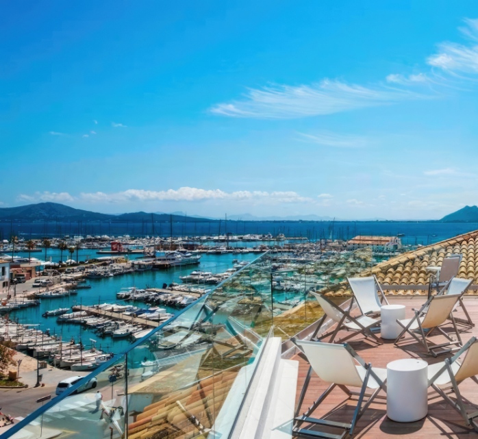 Terraza solarium del hotel totalmente equipada con vistas al Club Naútico de Puerto Pollensa y la bahía de Pollensa 