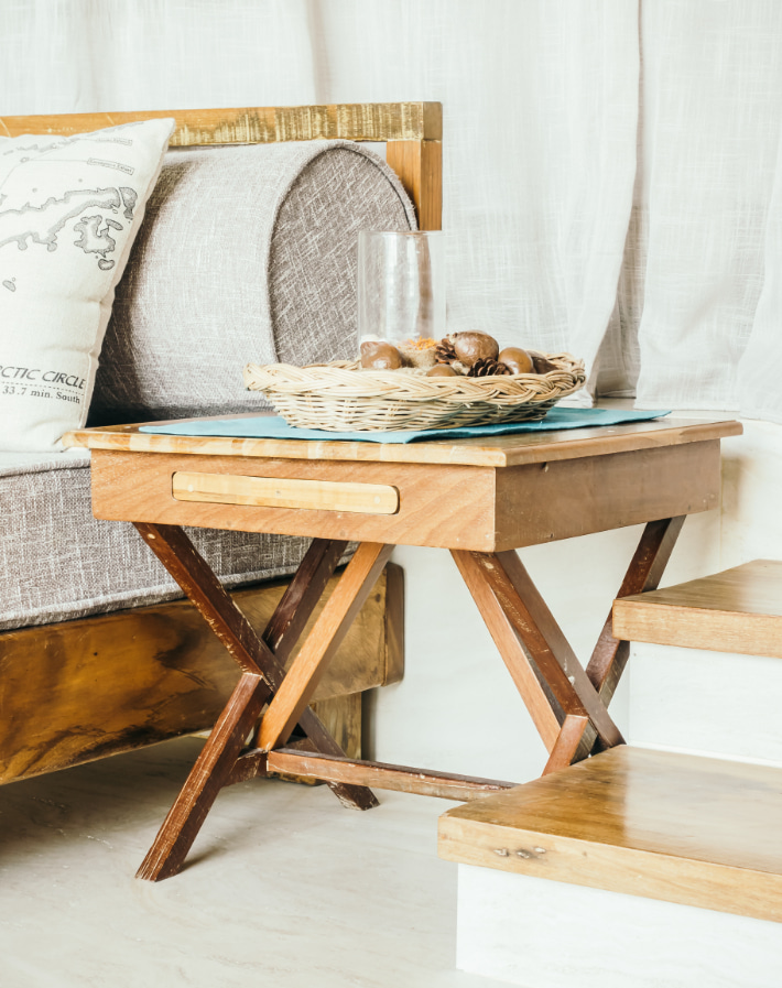 Mesita de noche de madera rodeada de muebles también con acabado de madera